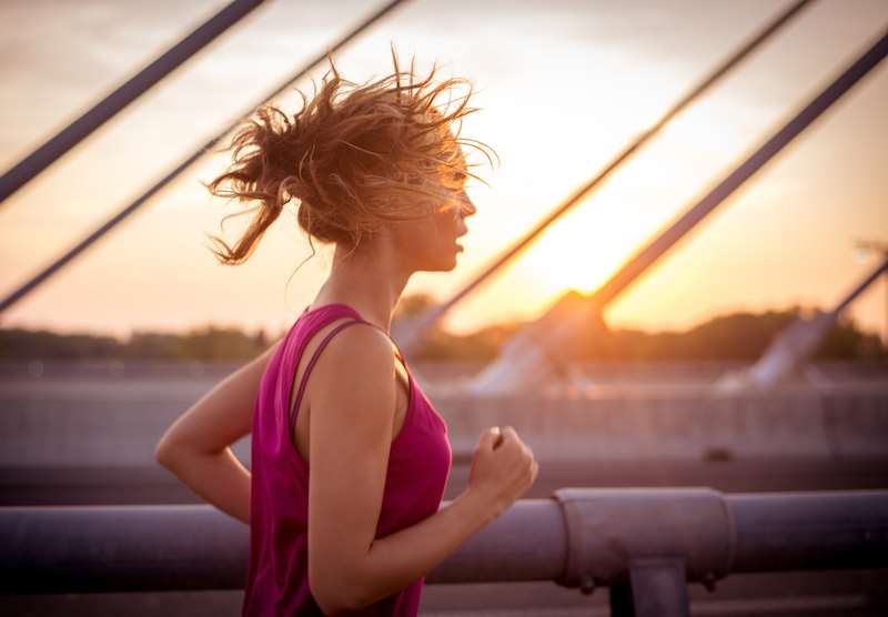 Mulher praticando corrida ao amanhecer.