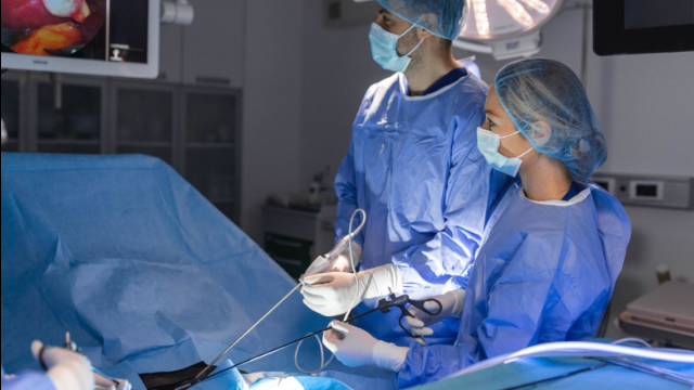 O cirurgião está perfurando o instrumento no abdômen do paciente. O cirurgião está realizando uma cirurgia laparoscópica na sala de cirurgia. Cirurgia minimamente invasiva