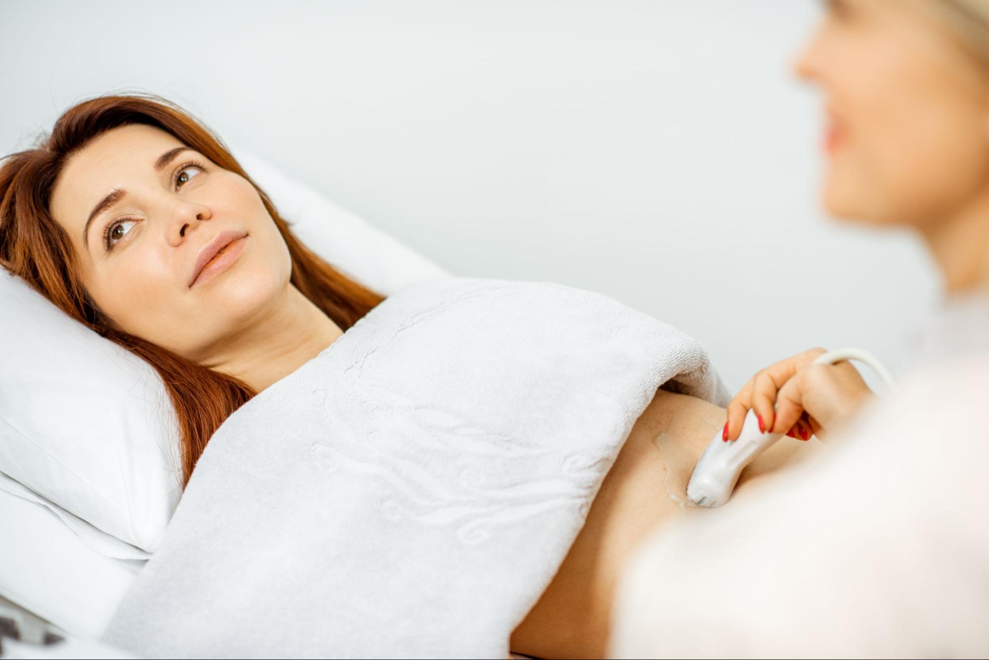 Mulher examinando seus órgãos pélvicos com sensor de ultrassom. Conceito de diagnóstico por ultrassom da saúde feminina.