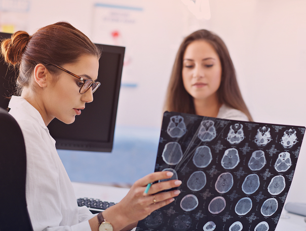 médica examinando tomografia do cérebro e explicando para sua paciente