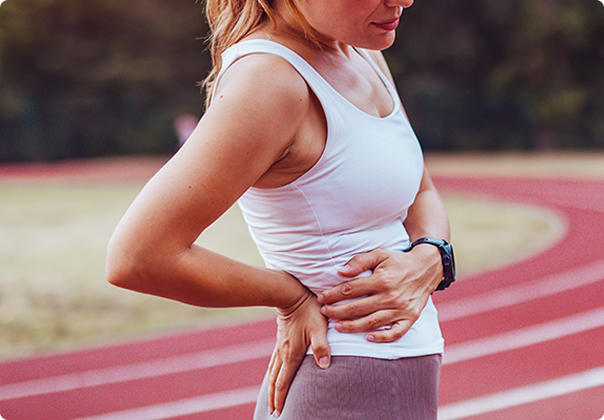 mulher com dor na lombar em pista de corrida