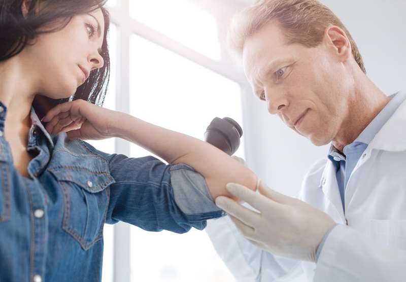 Médico examina paciente com suspeita de câncer de pele