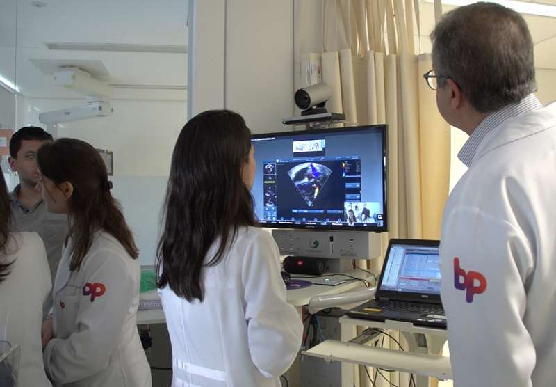 Doutora Juliana Pacheco fala com os especialistas de Pittsburgh por meio de sistema de videoconferência, que mostra na tela o resultado do ecocardiograma do paciente.