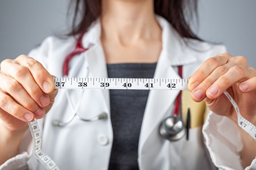 Médica com uma fita metrica.