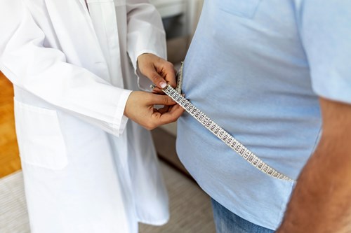 Médica tomando medidas de paciente obeso. 
