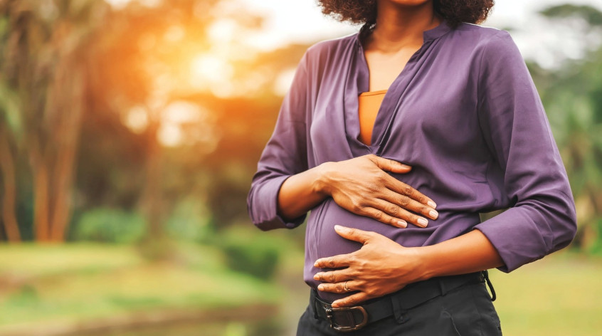 Uma mulher grávida com as mãos sobre a barriga