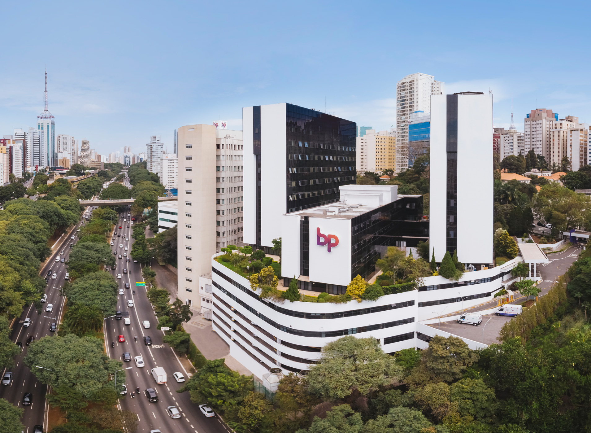 Foto aérea do Hospital BP, mostrando a fachada do prédio, a logomarca do hospital e a rua da frente com carros em movimento