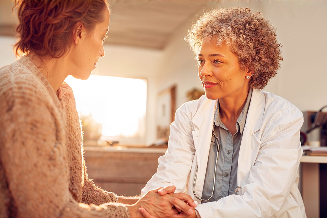 Uma mulher segurando as mãos de uma paciente em um consultório