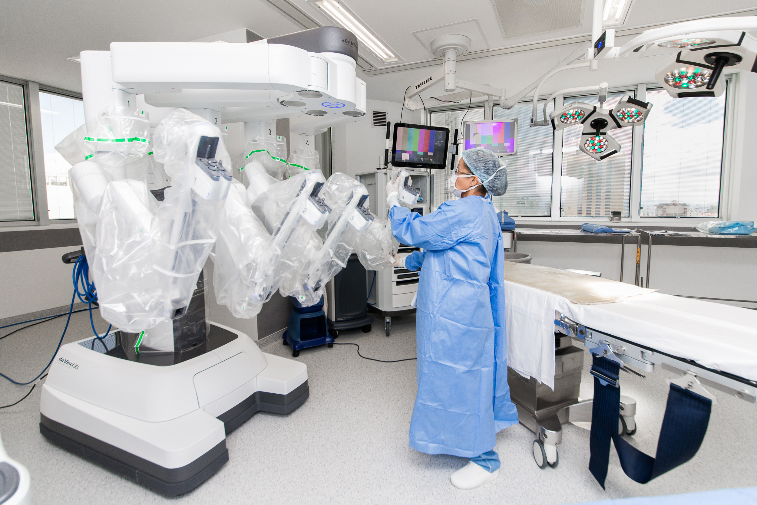 Médico na sala cirúrgica com o robô da Vinci durante procedimento cirúrgico.