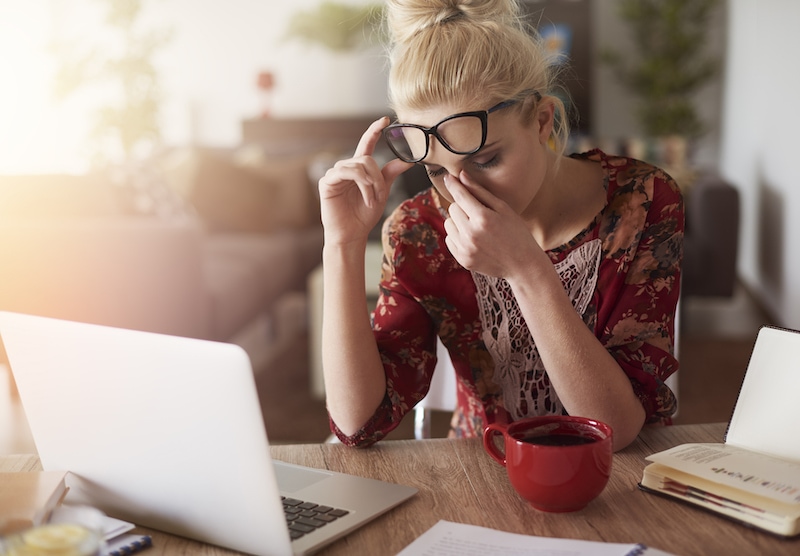 Mulher com dor de cabeça enquanto trabalha.