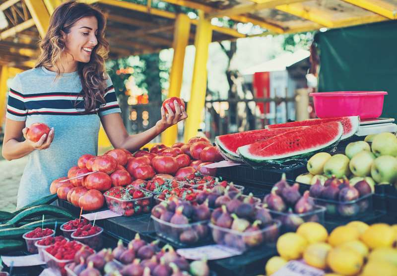 Mulher escolhe frutas em uma feira.