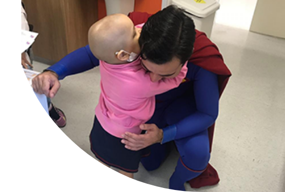 Foto de uma criança abraçando homem vestido de super heroi