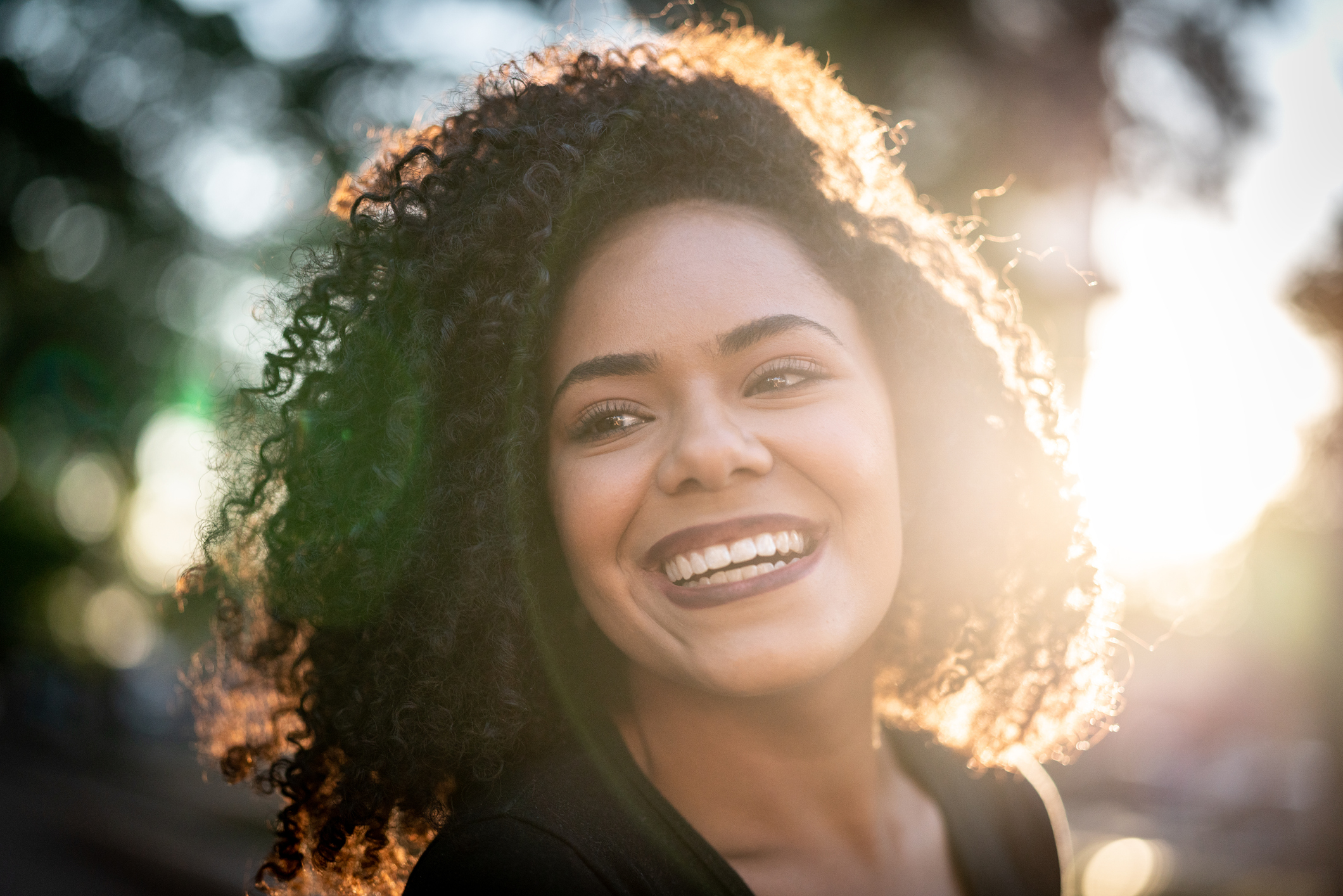 Imagem de uma mulher de cabelos cacheados sorrindo